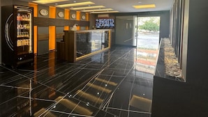 Um lobby moderno com um balcão de recepção, um relógio digital e uma máquina de venda automática.