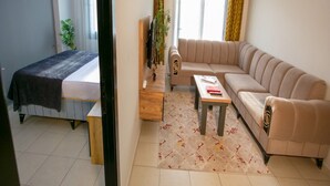 Uma sala moderna com sofá, mesinha, cama e janela com cortinas.