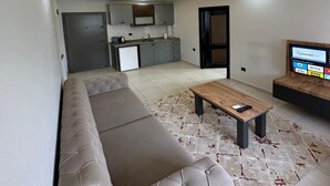 A modern living room with a sofa, a coffee table, and a TV. - LOCA MARİN OTEL (Kocasinan)