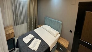 A modern hotel room with a bed, bedside tables, a wooden nightstand, a window with curtains, and a door. - LOCA MARİN OTEL (Kocasinan)