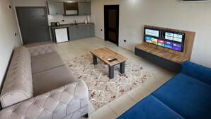 Uma sala de estar moderna com um sofá, uma mesa de centro e uma TV fixada na parede.
