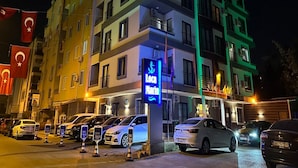 Um hotel com vários andares e varandas, com uma placa visível do 'Loca Marina Hotel' e diversos carros estacionados em frente.