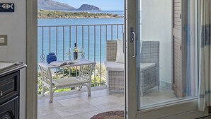 Ein Balkon mit Tisch, zwei Korbstühlen, einer Weinflasche und Gläsern.