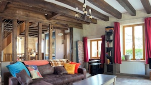 A rustic living room with exposed wooden beams, a leather sofa, a coffee table, and a bookshelf. - 16th-century Tourangelle between Beauval and Chenonceaux (Montrichard Val de Cher)