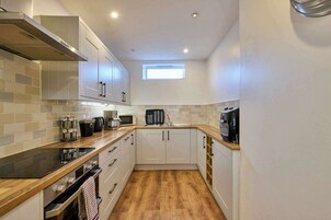 Una cocina compacta con armarios blancos, un microondas, un hervidor y una cafetera.