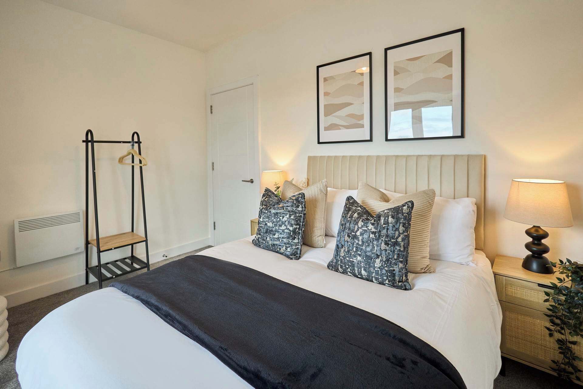A hotel room with a bed, bedside table, lamp, and artwork on the wall.