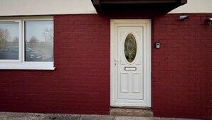 A red brick house with a white door, a window, and a small porch. - Host Stay Carlisle (Carlisle)