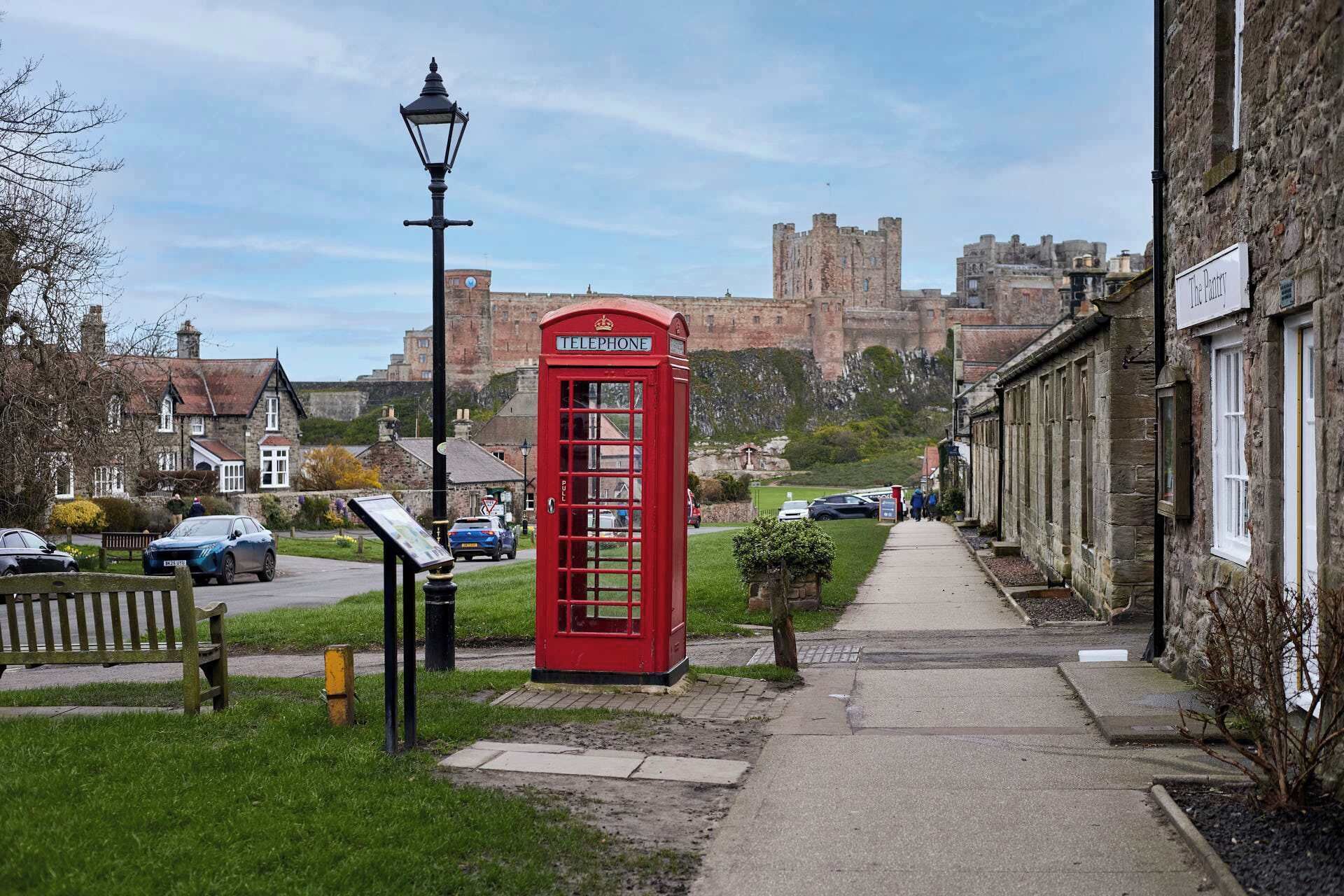 Eine rote Telefonzelle im britischen Stil, eine Straßenlaterne und ein Schloss im Hintergrund.