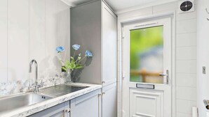 Een moderne keuken met een marmeren aanrechtblad, een spoelbak en een deur met een geëtst glaspaneel.