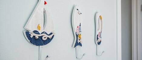 Three wall-mounted hooks with decorative items.