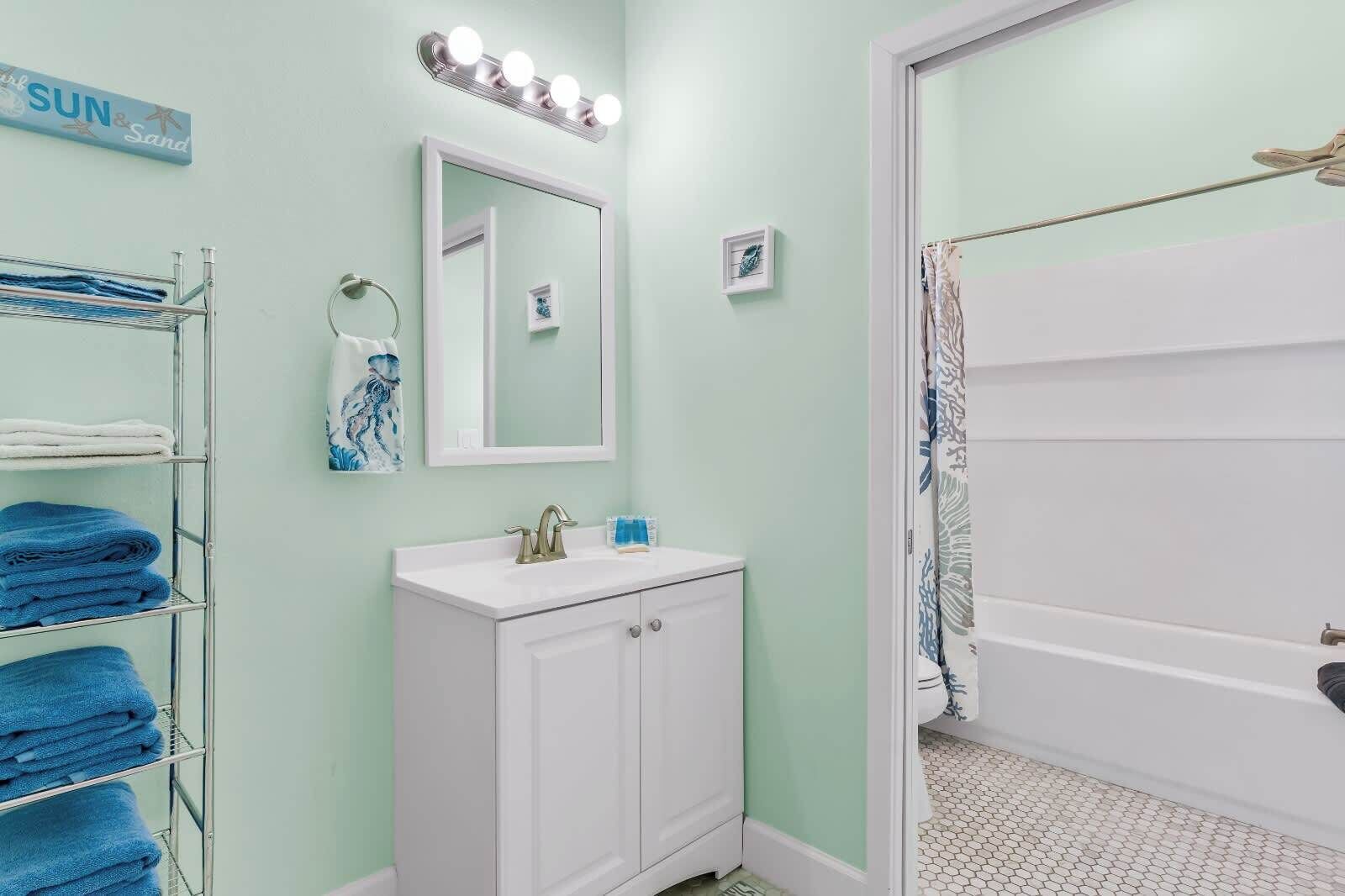 Une salle de bain avec un meuble-lavabo, un miroir et un porte-serviettes.