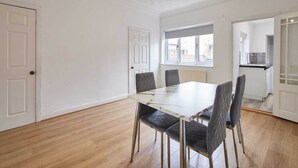 A dining area with a marble table, four chairs, and a view of a kitchen and a window. - Host Stay Houghton (Houghton le Spring)