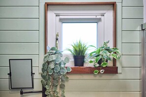 A window with a wooden frame, a potted plant, and a small shelf. - Host Stay Curlews Rest (Preston)