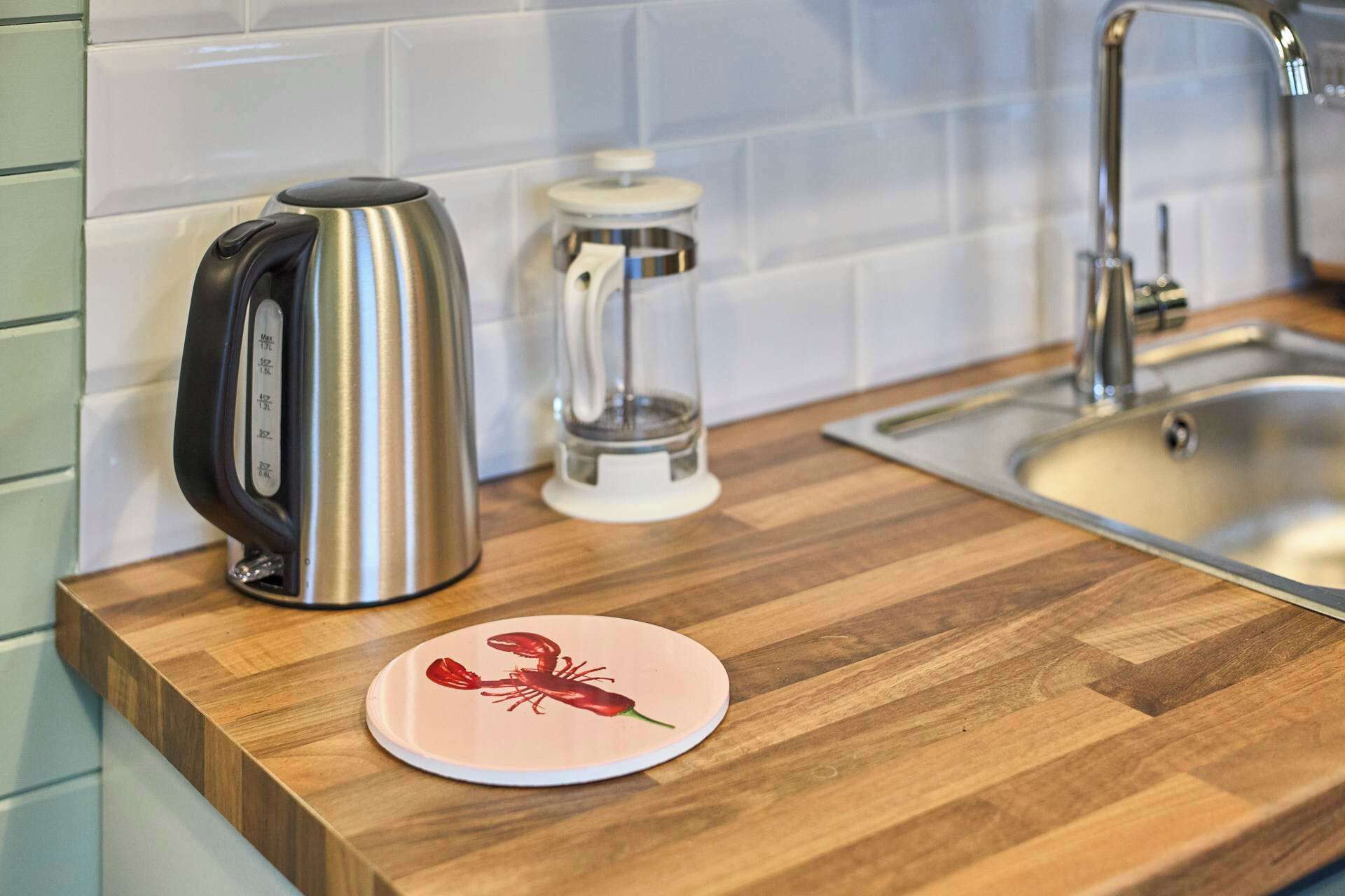 A kitchen counter with a kettle, a glass container, and a lobster plate.