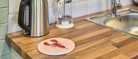 A kitchen counter with a kettle, a glass container, and a lobster plate.