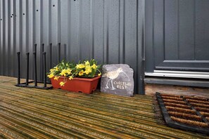 A potted plant with yellow flowers, a stone with a bird illustration, and a wooden bench with a striped pattern. - Host Stay Curlews Rest (Preston)
