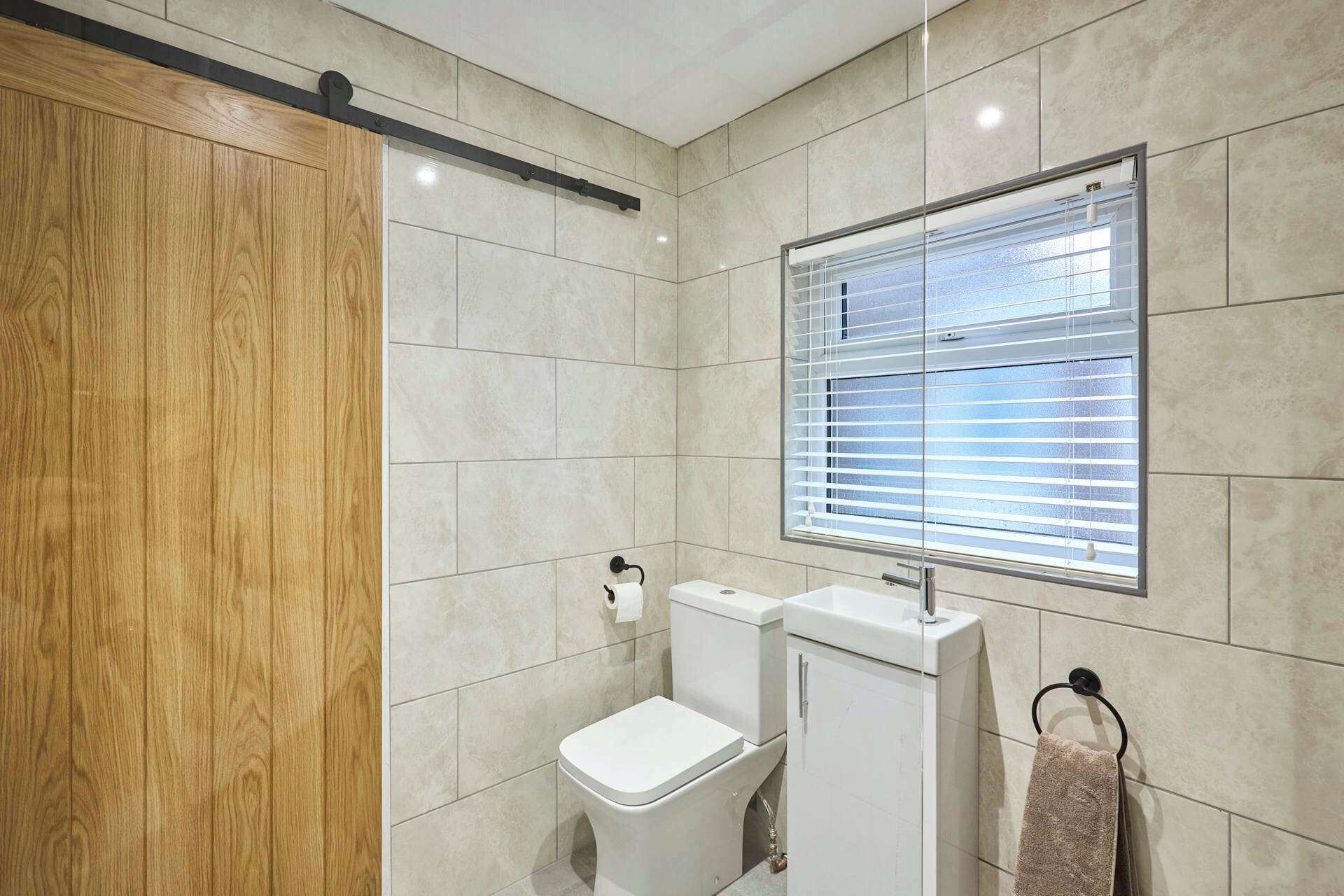 A bathroom with a toilet, sink, and window with blinds.