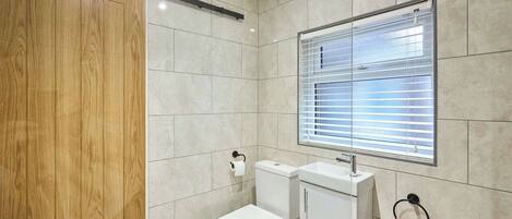 A bathroom with a toilet, sink, and window with blinds.