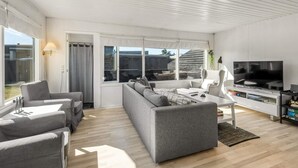 Uma sala de estar moderna com sofá, mesa de centro, TV e estante.