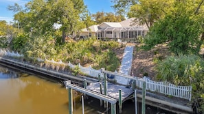 A house with a covered porch, a dock extending into a body of water, and a white picket fence. - Waterfront 3B Free Dock Heated Pool Hot Tub Gym (Port Charlotte)