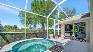 Un espace extérieur abrité comprenant un jacuzzi, des sièges et une vue sur les arbres.