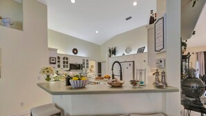 Une cuisine moderne dotée d’un îlot central, de tabourets de bar et de divers appareils de cuisine.