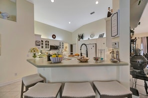 A modern kitchen with a central island, bar stools, and various kitchen appliances. - Waterfront 3B Free Dock Heated Pool Hot Tub Gym (Port Charlotte)