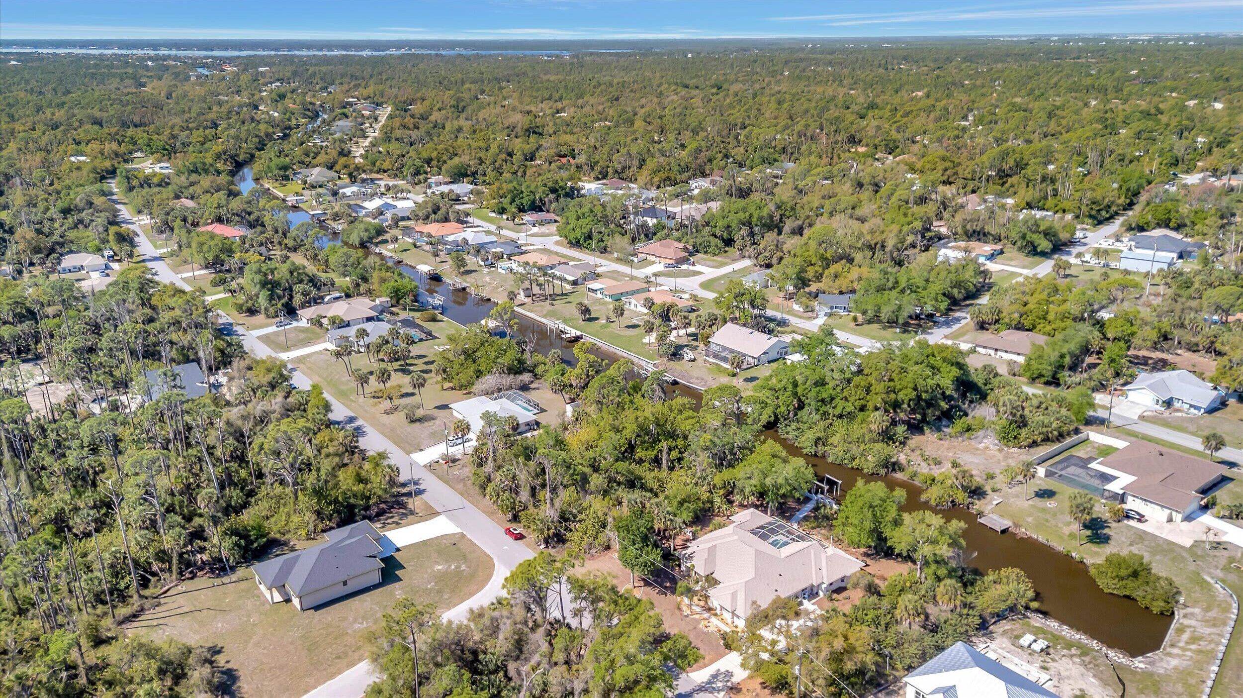 An aerial view of a residential area with houses, roads, and a river.
