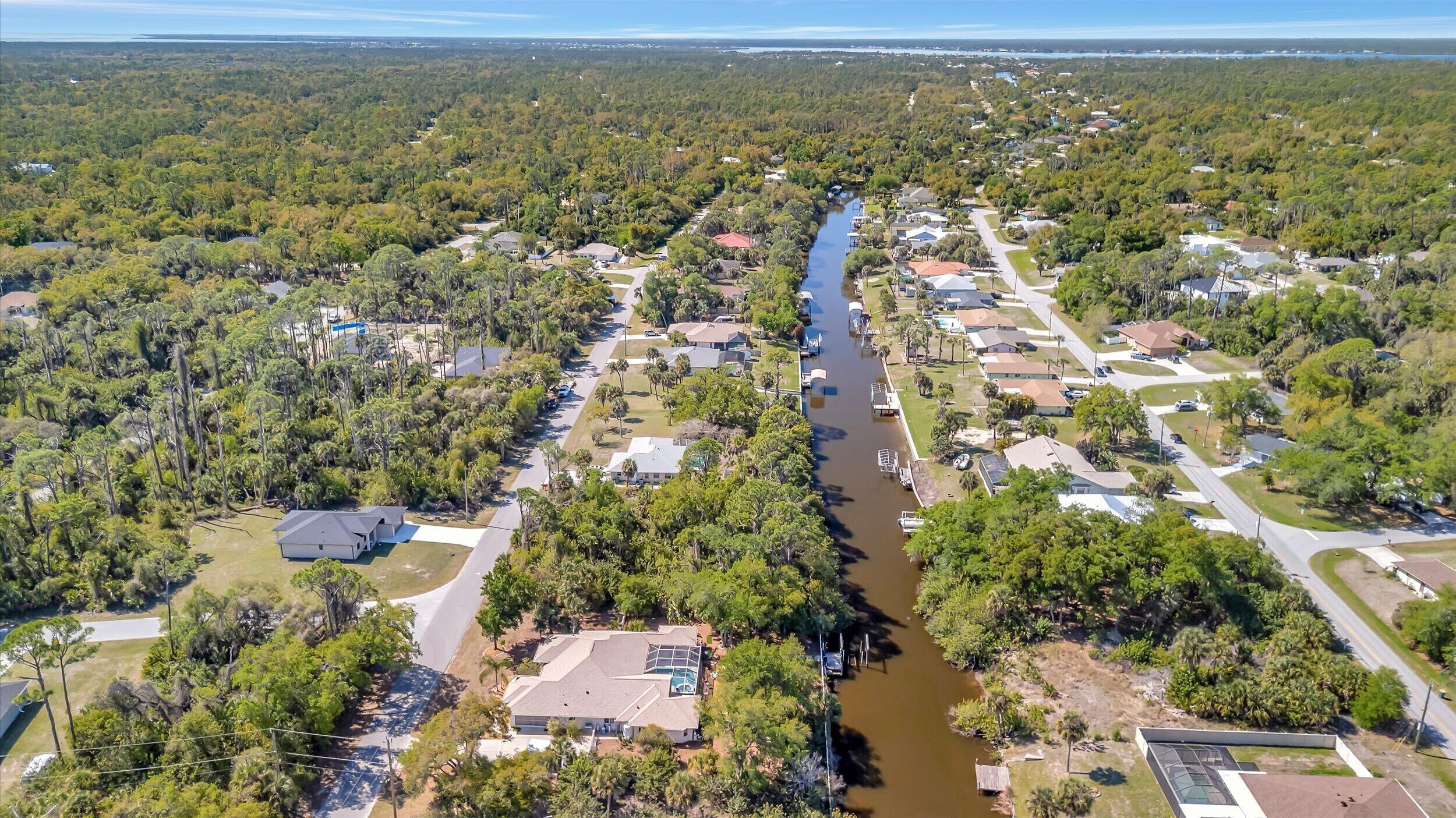 An aerial view of a residential area with houses, a river, and dense greenery.