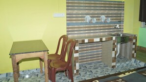 A small kitchen with a wooden table, two chairs, a sink, and a tiled backsplash.