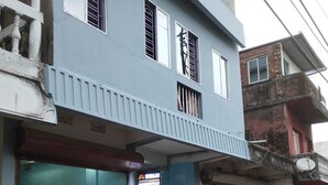 Ein zweistöckiges Gebäude mit blauer Fassade, einem verschlossenen Eingang und einem sichtbaren Geschäft im Erdgeschoss.