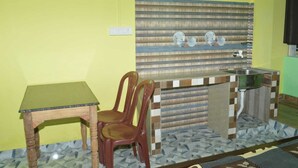 Eine kleine Küche mit Holztisch, zwei Stühlen, einem Spülbecken und einer gefliesten Spritzschutzwand.