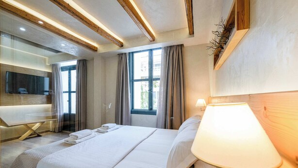 Ein Hotelzimmer mit Bett, Fernseher, Schreibtisch und einem Fenster mit Vorhängen.
