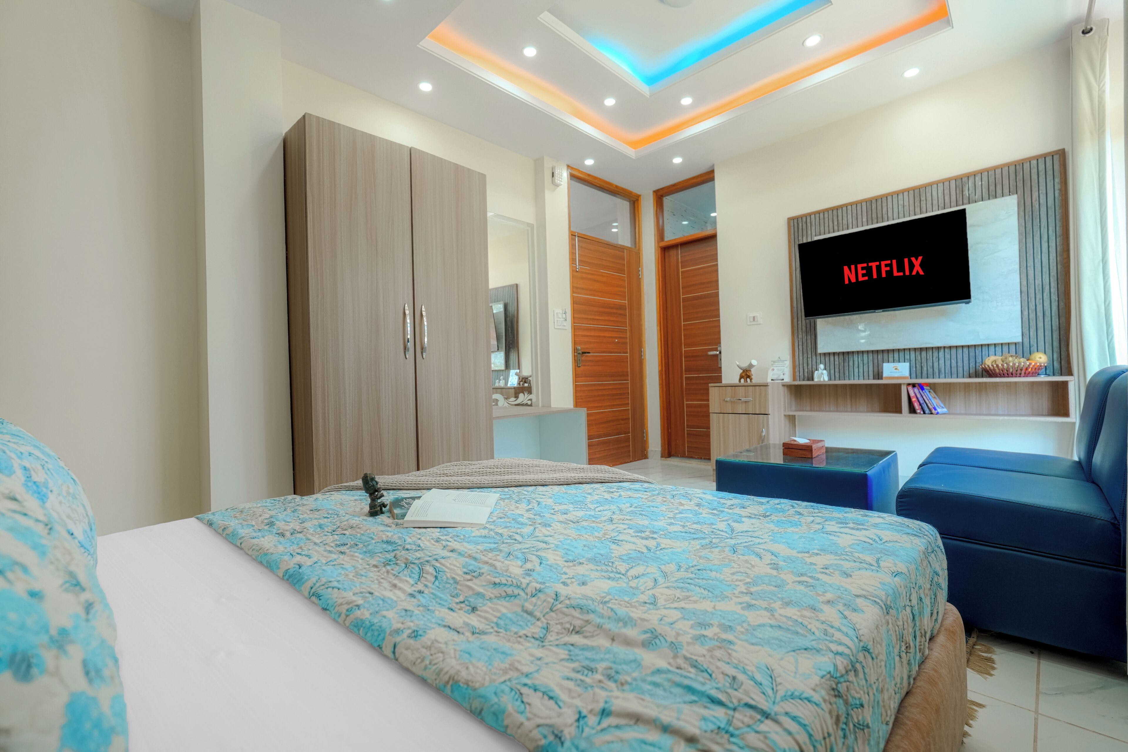 A modern hotel room with a large bed, a TV mounted on the wall, and a wardrobe.