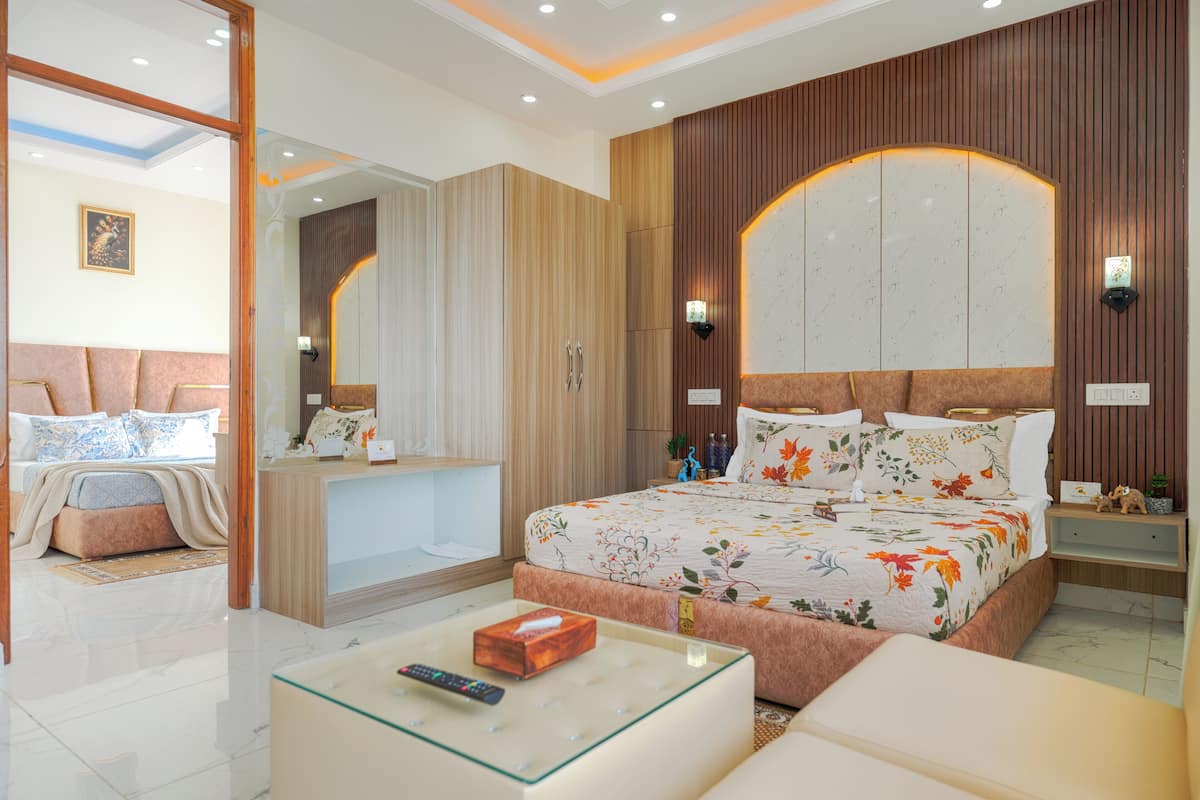 A bedroom with a large bed, a bedside table, a nightstand, a mirror, and a wall-mounted light fixture.