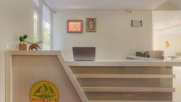 A reception desk with a laptop, framed artwork, and a logo on the wall.