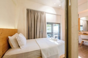 Ein Hotelzimmer mit Bett, Holz-Kopfteil, Vorhängen am Fenster und Blick nach draußen.