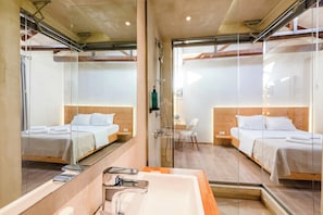 Ein modernes Hotelzimmer mit zwei Betten, einem großen Spiegel, einer Dusche und einem Badezimmer mit Waschbecken und Spiegel.