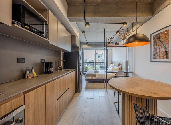Une cuisine moderne avec des meubles en bois, un four à micro-ondes encastré et une machine à café.