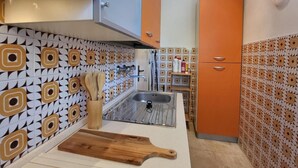 A kitchen with patterned tiles, a sink, wooden utensils, and a cutting board. - Villa Isabella Guest House - with Garden, Parking and WiFi (Ostuni)