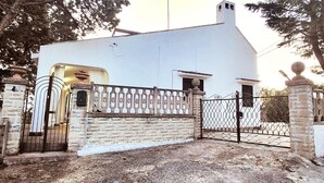 A white building with a gated entrance, stone walls, and a small porch. - Villa Isabella Guest House - with Garden, Parking and WiFi (Ostuni)