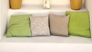 A white bench with green and patterned cushions, flanked by two potted plants, and a dark brown shutter above. - Villa Isabella Guest House - with Garden, Parking and WiFi (Ostuni)
