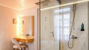 A hotel room with a desk, chair, mirror, and a glass-enclosed shower area. - Panellinion Beachfront Gem, Comfy Double Sea Nest (Kalamata)