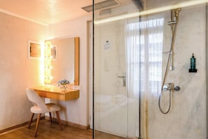 A hotel room with a desk, chair, mirror, and a glass-enclosed shower area. - Panellinion Beachfront Gem, Comfy Double Sea Nest (Kalamata)