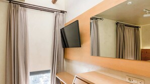 A room with a wooden desk, a chair, a TV mounted on the wall, a large mirror, and a skylight. - Panellinion Beachfront Gem, Comfy & Sunny Triple (Kalamata)
