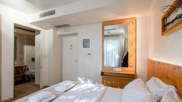 A hotel room with a bed, a mirror with lights, a wooden headboard, a desk, and a chair. - Panellinion Beachfront Getaway - Sea Sunny Gem (Kalamata)