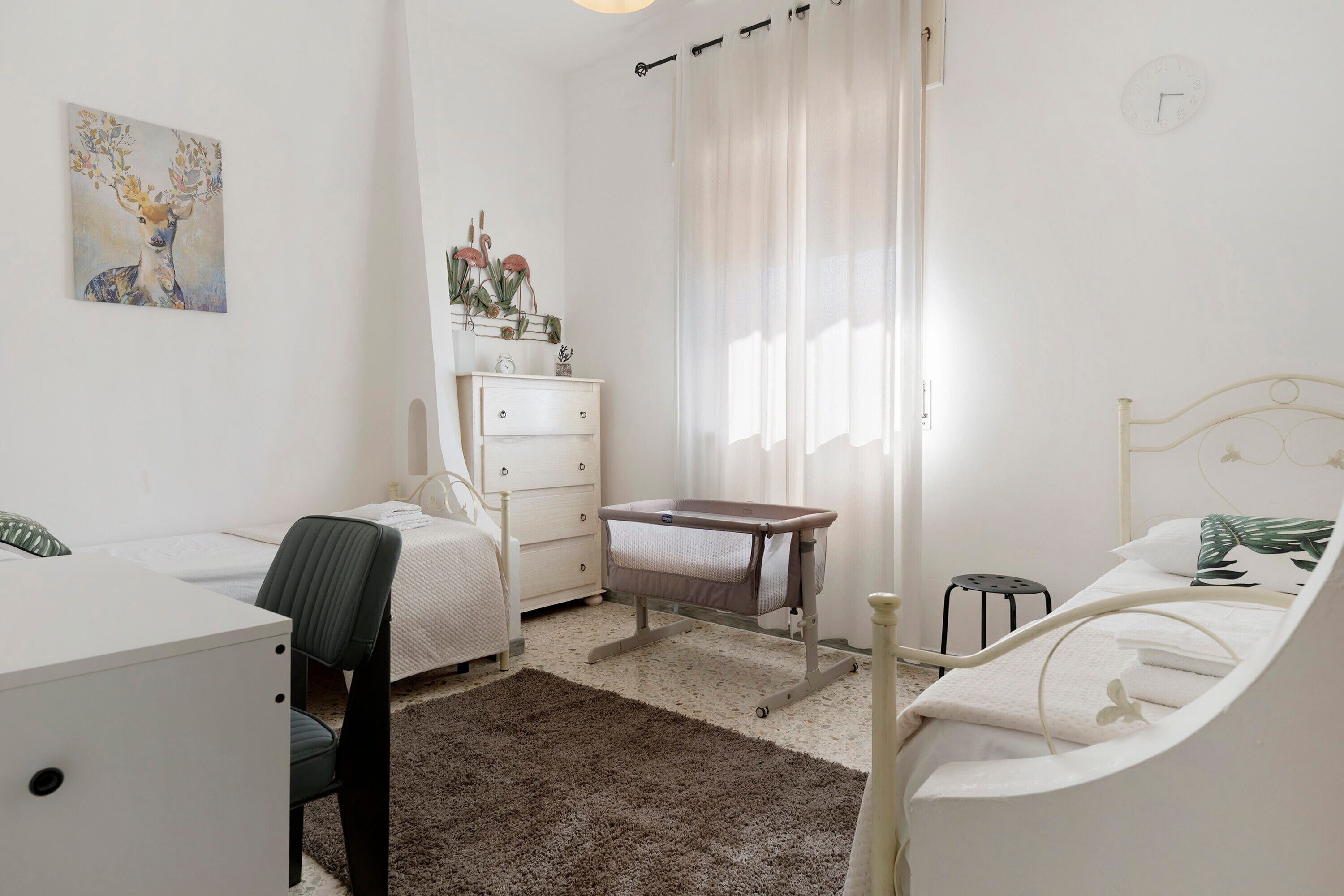 Une chambre à coucher comprenant un lit, un bureau, une chaise, une commode et un berceau.