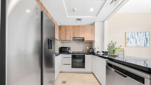 Eine moderne Küche mit Edelstahlgeräten, Holzschränken und einer schwarzen Arbeitsplatte.