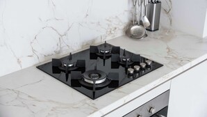 A kitchen with a black gas stove, a marble countertop, and stainless steel utensils hanging on the wall. - Free Housekeeping Visits During Your Stay - Stayshort - Relaxing 1 Bed That Sleeps 4 With Amazing Views From Balcony (Dubai)