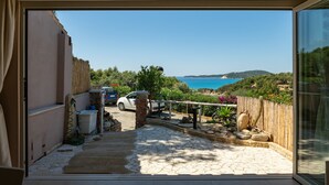 Un chemin de pierres mène à une voiture garée devant une maison qui offre une vue sur la mer.